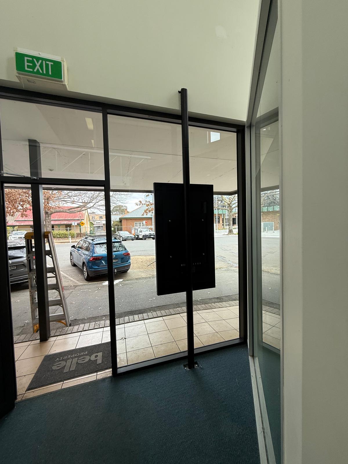 Wider rear view showing the full height of the floor-to-ceiling mounting system and how the display is positioned within the glazed shopfront.
