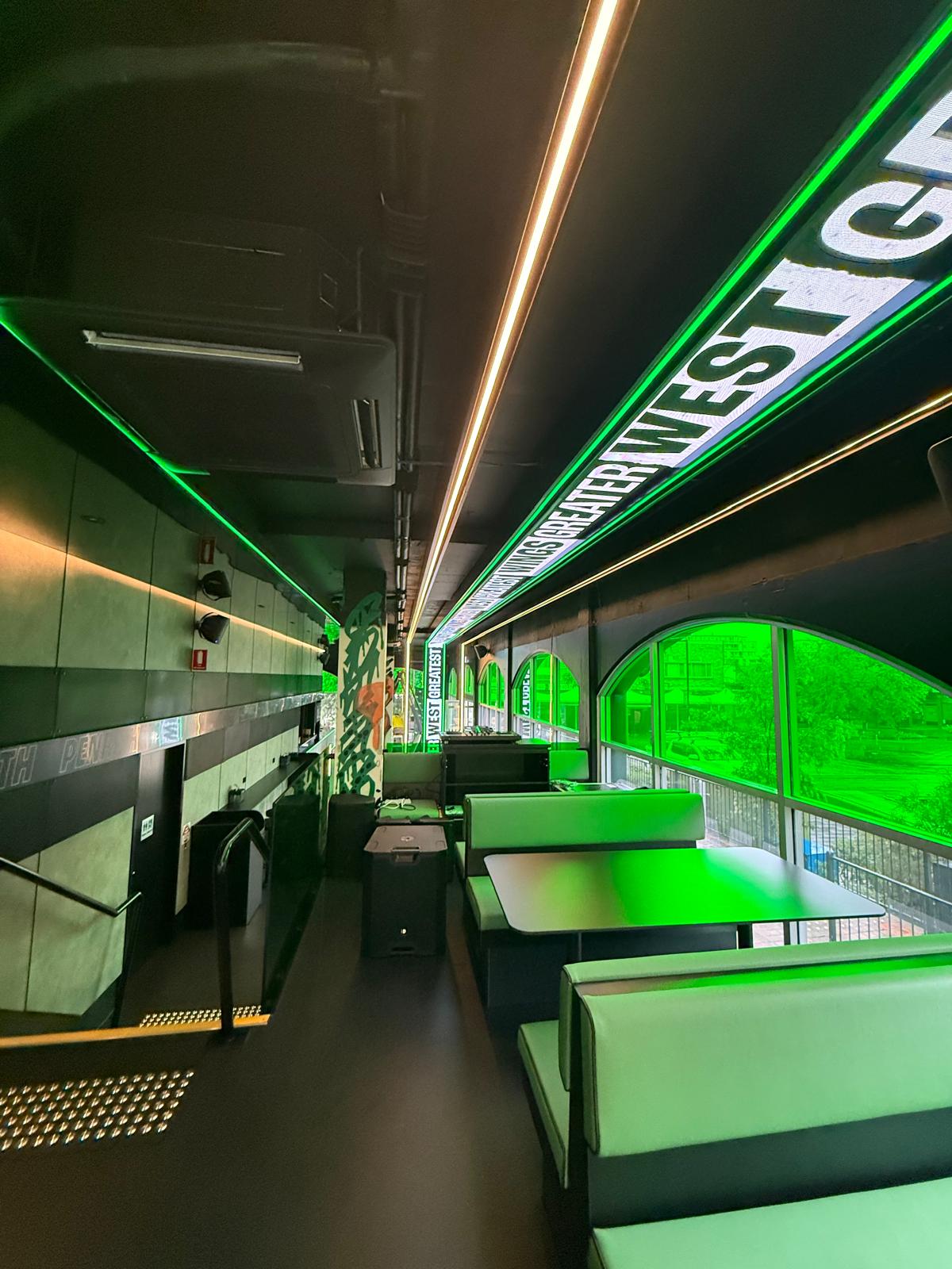 Full hospitality LED installation showing the ceiling ribbon display integrated above booth seating and venue circulation areas.