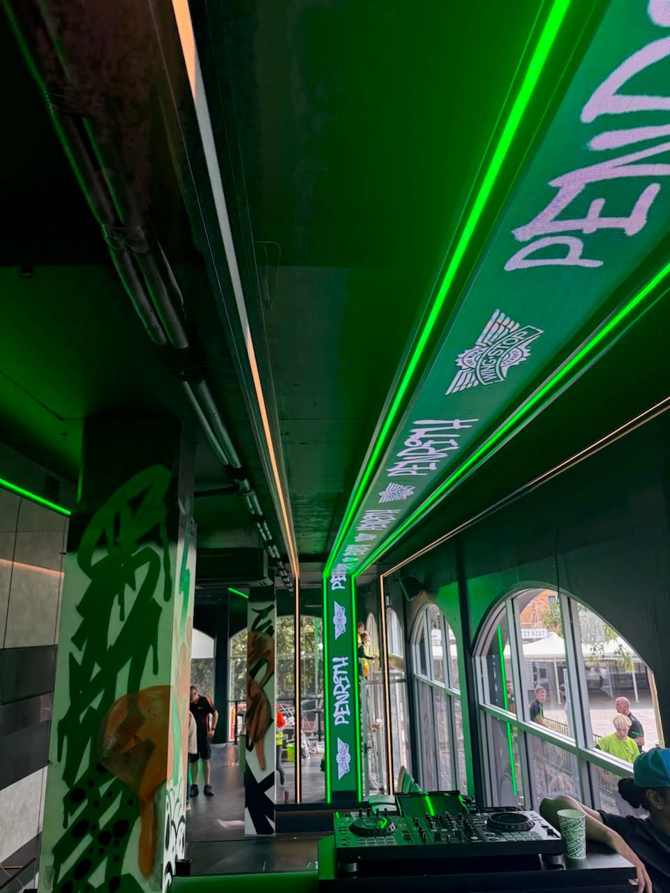 Long-format LED ribbon display integrated into the venue architecture above the seating and service areas.