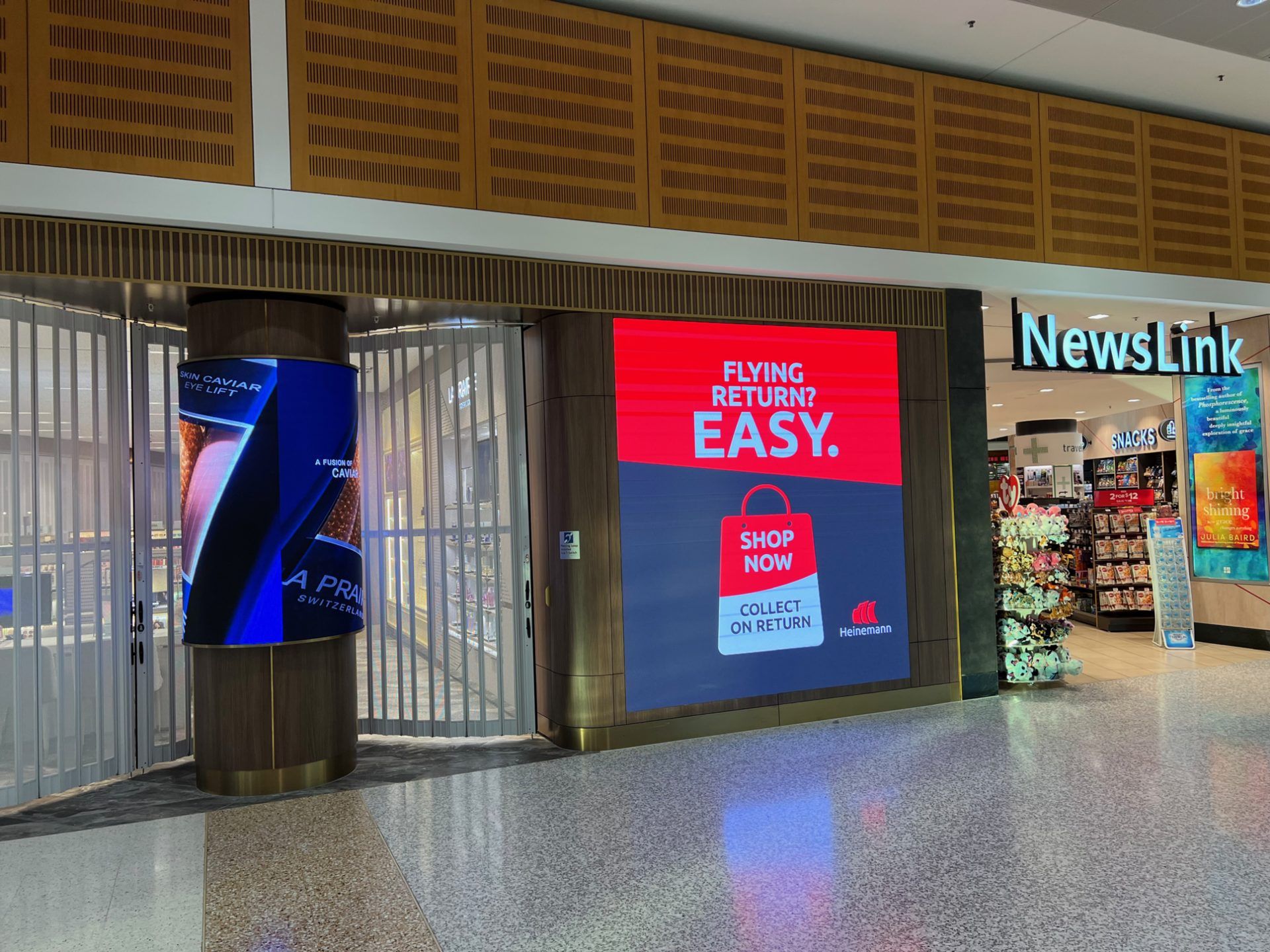 Curved column LED display and large-format wall-mounted LED screen at a duty-free storefront entrance.
