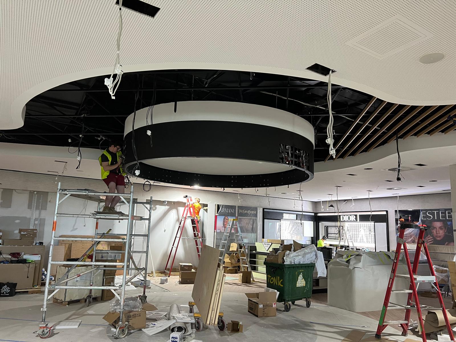 The halo display now integrated into the finished ceiling cove, with the surrounding retail floor nearing completion.