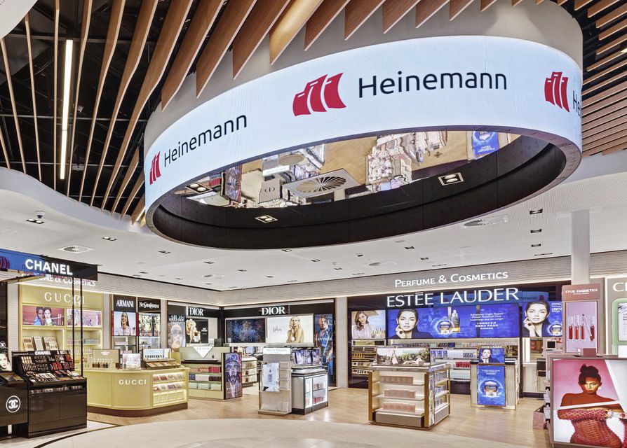 Suspended circular halo LED display above the Heinemann airport retail environment.