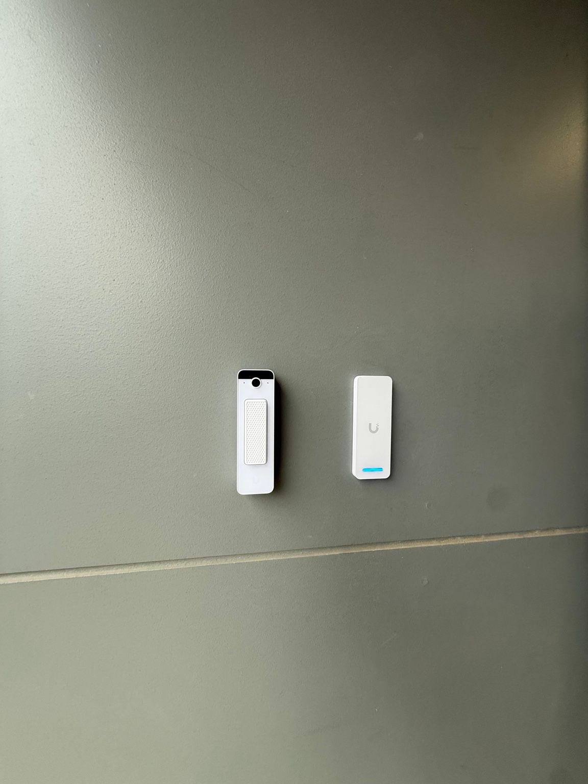Wall-mounted access control and door entry hardware, showing a compact intercom/entry device alongside a networked access control reader.