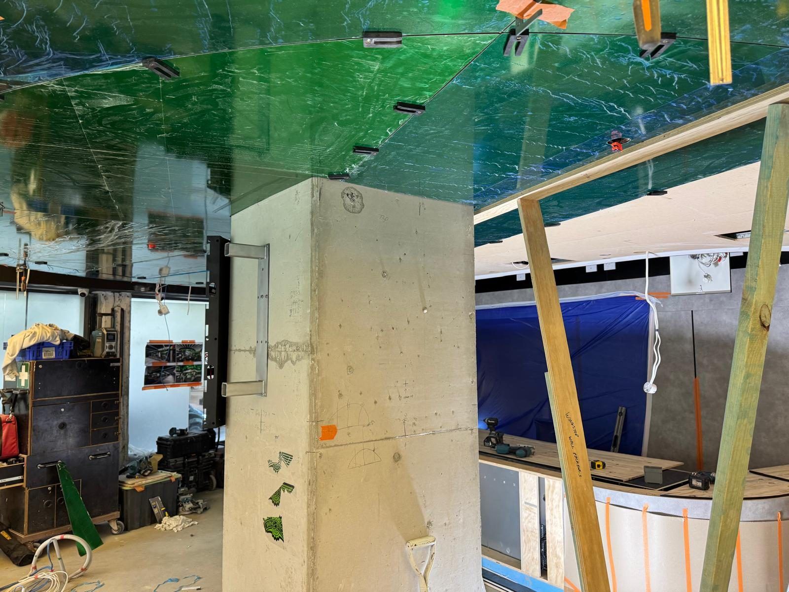 Early fit-out at a Wingstop store, showing the curved ceiling structure still protected under plastic film alongside site tools and equipment.
