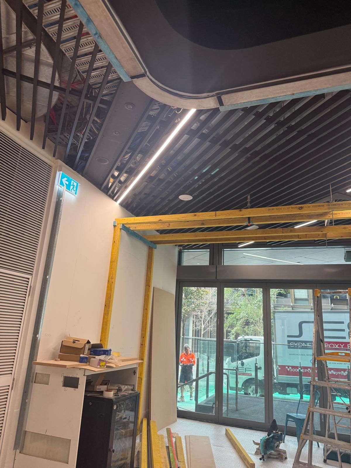 Curved soffit framing under construction at the store entry, viewed from inside toward the street-facing shopfront.